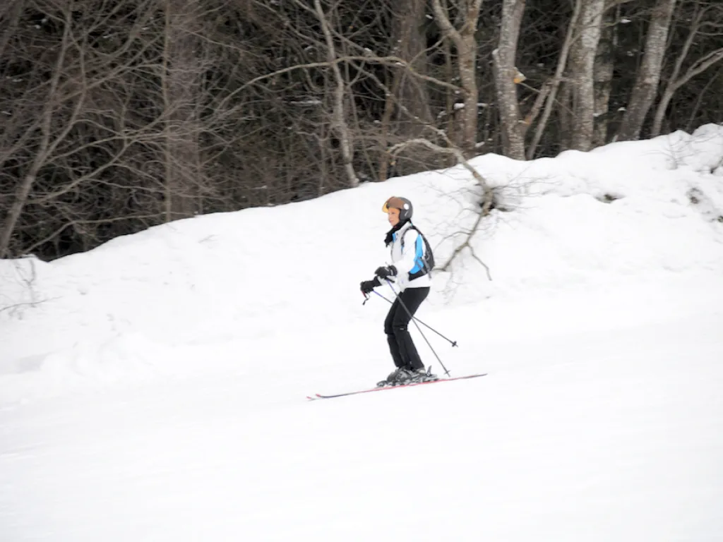 Skifahrerin quert den Hang am Waldrand.